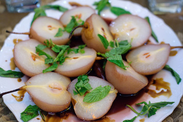 Appetizer of half pears sprinkled with fresh mint leaves on a festive table