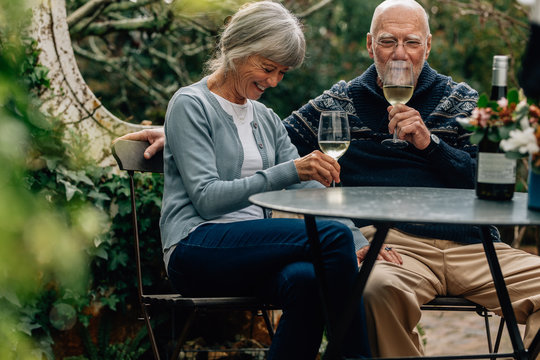 Old couple enjoying a glass of wine sitting together