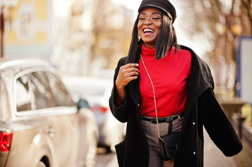 African american fashion girl in coat and newsboy cap posed at street.