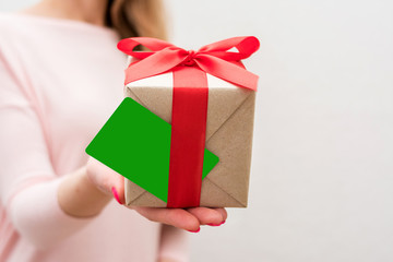Woman holding a box with a gift, business card to the camera, front view, close up, background with copy space, for advertising or slogan