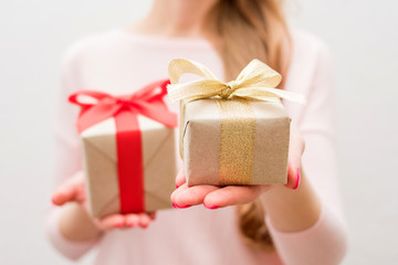 Woman holding a boxs with a gifts, gift with red ribbon, gift with gold ribbon, on camera, front view, close up