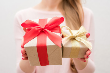 Woman holding a box with a gifts, gift with red ribbon, gift with gold ribbon, on camera, front view, close up