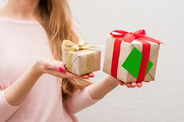 Woman holding a box with a gifts and business card to the camera, front view, close up, background...