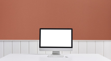 Desktop screen on the white table brown wall and white table.
