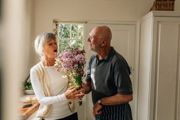 Senior man giving a bouquet to his wife - Powered by Adobe