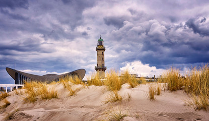 Lighthouse at the Teepott behind the dunes in Warnemünde. - obrazy, fototapety, plakaty