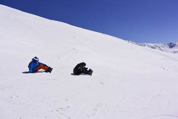 Dos patinadores de snowboard estan en la ladera de una montaña cubierta de nieve