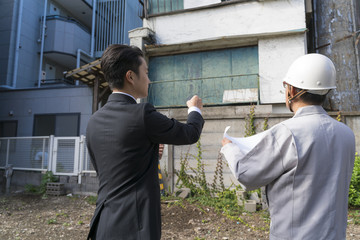 不動産デベロッパー イメージ・建物取り壊し工事・打ち合わせをする営業マンと施工業者