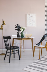 Lastrico poster on empty wall of elegant dining room with round wooden table with black leaf in metal vase and white flowers in glass vase
