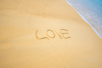 write text on sand LOVE at the sea. soft focus.