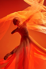 Young graceful female ballet dancer or classic ballerina dancing at red studio. Caucasian model on pointe shoes © master1305