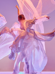 Young graceful female ballet dancer or classic ballerina dancing at pink studio. Caucasian model on...