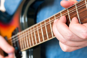 Obraz premium Hands of a musician in a denim shirt playing vintage sunburst guitar