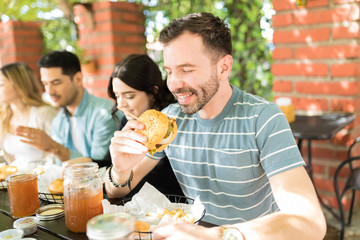 Young Man Eating Tasteful Hamburger