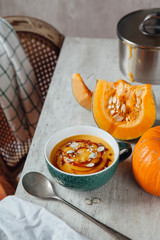 Pumpkin soup with seeds and spicy sauce on the table with fresh sliced pumpkin