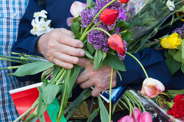 Fototapeta na wymiar The old hands of a veteran of the second world war hold a bouquet of flowers