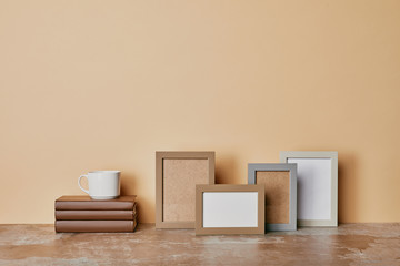 Photo frames, books and cup of coffee on beige background