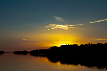 A beautiful deep blue sky at sunset accented by a white spangled cloud, a few days after midsummer, viewed from a cove on the Island of Nicklösa in the Åland Islands, Finland.