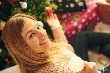 Portrait of beautiful woman with christmas presents near christmas tree.