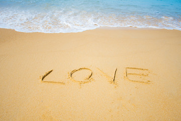 write text on sand LOVE at the sea. soft focus.