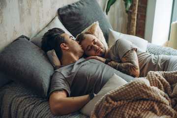 Peaceful european gay couple sleeping at home embracing and spending weekend together. Homosexual love concept - obrazy, fototapety, plakaty