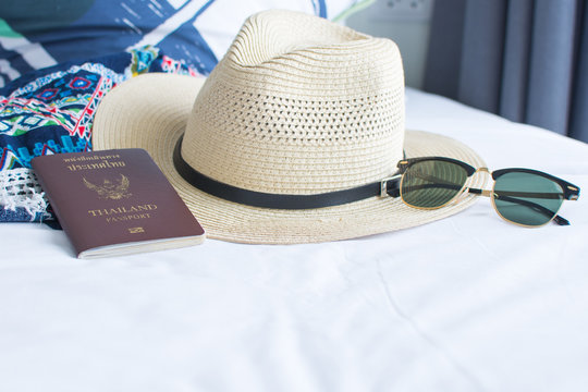 passport, hat, and sunglasses on withe bed, accessories for the trip. soft focus.