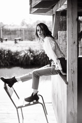 Atmospheric portrait of a beautiful lonely girl walking around a wooden house on the water at the lake