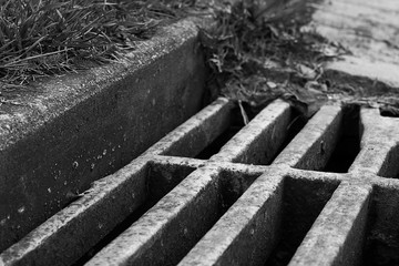 Black and white sewer grate is close