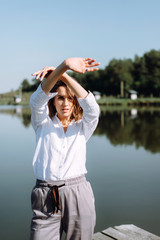 Portrait of beautiful woman near a wooden bridge by the lake at sunny day. Atmospheric portrait of a lonely girl walking