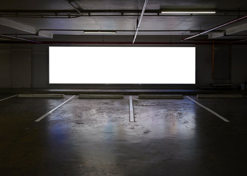 Empty Indoor car park with blank billboard at night time