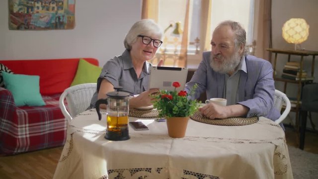 Lovely elderly retired family couple watching family photos