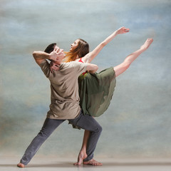 Naklejka premium Two people dancing in contemporary stile of ballet at studio on gray