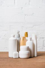 White and golden plastic bottles on wooden table on brick wall background