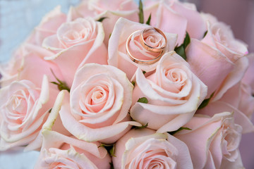 two wedding rings lying on colorful bouquet pink roses, close up