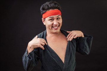 Funny karate fighter wearing black kimono flirting to the camera. Do you like me zy smiling man...