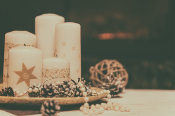 Christmas and New Year background with holiday decoration - candles and cones with lights and festive bokeh, vintage image