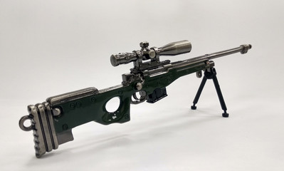 A miniature model of military sniper automatic gun in small-scale isolated on white background....