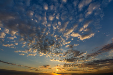 Panorama of sky at sunrise or sunset. Beautiful view of dark blue clouds lit by bright orange yellow sun on clear sky. Beauty and power of nature, meteorology and climate changing concept.