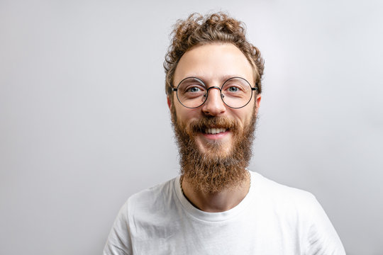 Portrait of young handsome hipster man with beard smiling laughing looking at camera over white background.