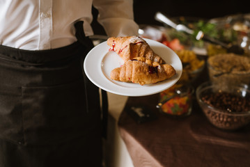 A waiter holding a plate with croissants at the restaurant