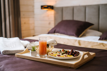 Breakfast in bed with juice and scrabled eggs with sausages