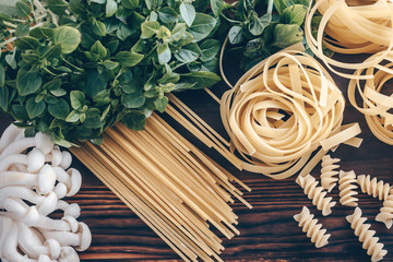 Different types of  uncooked pasta on wooden background. Fettuccine, spaghetti and fusilli with...
