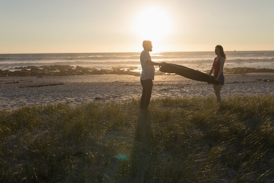 Couple hoding blanket on beach
