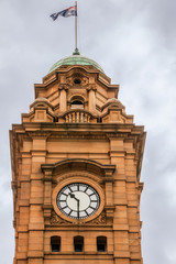 Hobart, Tasmania, Australia - December 14, 2009:  Historic brown stone Clock Tower on corner of Macquarie and Elizabeth streets against gray sky. Green dome with flag. Close up of the clock and top.