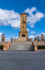 Fototapeta na wymiar Fremantle, Australia - November 25. 2009: Front side of brown-beige tower at war memorial under blue sky with white clouds remembering world war one. Lanterns and stairway.