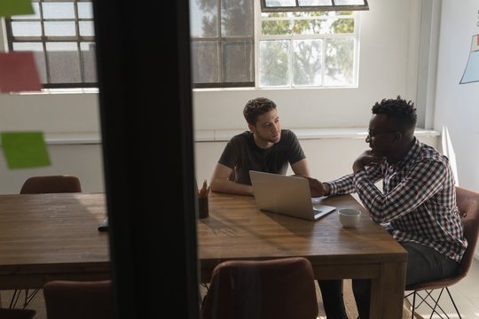 Executives discussing over laptop in conference room