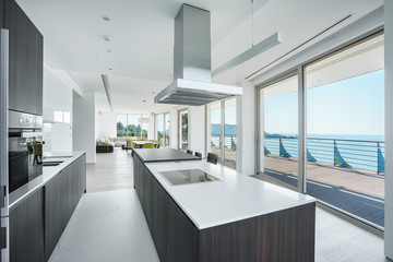 Interior of light spacious kitchen with large panoramic windows in a luxury villa