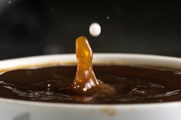 Beautiful bursts of milk drops on the surface of the coffee closeup