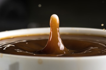 Beautiful bursts of milk drops on the surface of the coffee closeup