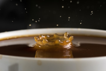 Beautiful bursts of milk drops on the surface of the coffee closeup